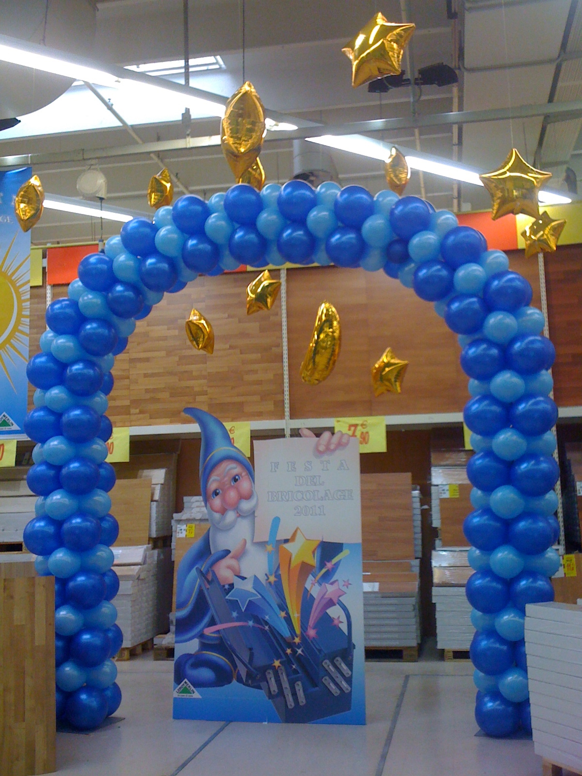 Allestimenti con palloncini e animazioni, arco di palloncini blu e azzurro e stelle dorate appese al soffitto.